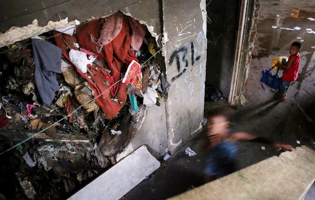 Youngsters gather in an occupied building in the Mangueira “favela” community, before the Brazil-Germany soccer final, on August 20, 2016 in Rio de Janeiro, Brazil. Hundreds of residents who live in the surrounding structures must collect water from hoses as there is no running water in the buildings. Much of the Mangueira “favela” community sits about a kilometer away from Maracana stadium, the site of the closing ceremonies and today's Brazil-Germany soccer match during the Rio 2016 Olympic Games. (Photo by Mario Tama/Getty Images,)