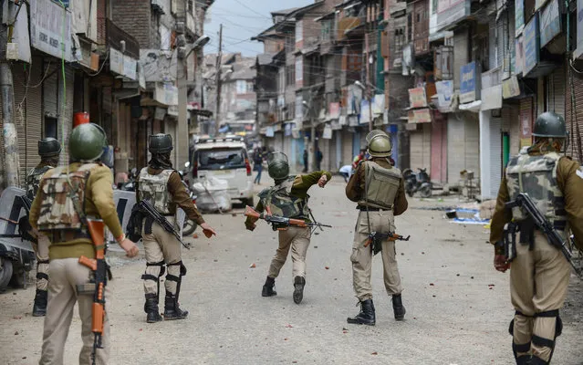 Indian police throw stones during clashes with flood-affected Kashmiri residents protesting against the state government in Srinagar on October 15, 2014. Kashmir was devastated last month by heavy monsoon rains and floods which killed more than 450 people in the region and caused billions of dollars in damage to homes, businesses and livelihoods.  Residents accuse the local government of a tardy response to the floods. (Photo by Tauseef Mustafa/AFP Photo)