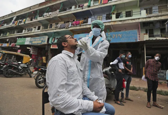 An Indian health worker takes a swab sample of a person for COVID-19 test in Ahmedabad, India, Friday, July 24, 2020. India is the third hardest-hit country by the pandemic in the world after the United States and Brazil. (Photo by Ajit Solanki/AP Photo)
