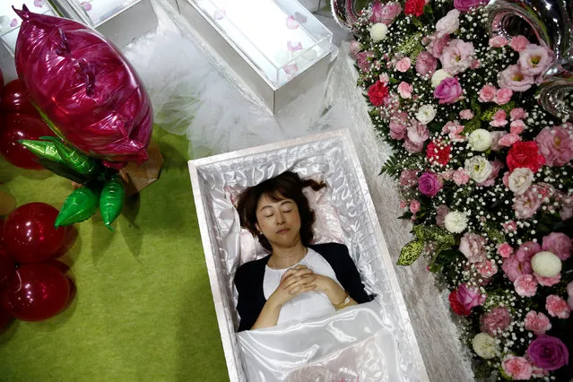 A staff lies in a casket next an altar decorated with flowers and balloons as she demonstrates Okuribito funeral's funeral service at the Life Ending Industry Expo in Tokyo, Japan, August 22, 2016. (Photo by Kim Kyung-Hoon/Reuters)