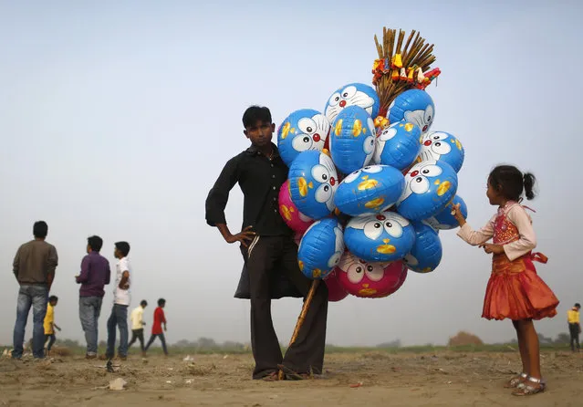 A vendor selling balloons waits for customers on the banks of the river Yamuna during the Hindu religious festival of Chatt Puja in New Delhi October 29, 2014. (Photo by Anindito Mukherjee/Reuters)