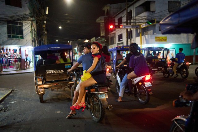 A couple traveling on a motorcycle waits at a traffic light in Iquitos, Peru, Monday, May 26, 2025. (Photo by Rodrigo Abd/AP Photo)
