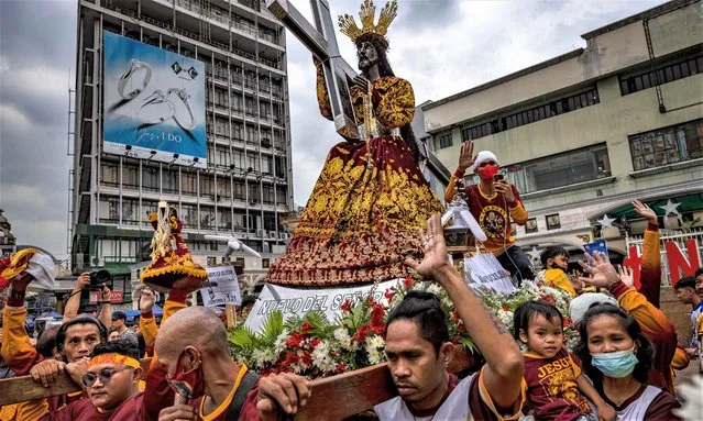 Filipino Catholic devotees jubilate as they are doused with holy water, during a parade of Black Nazarene replicas ahead of the Feast of the Black Nazarene, outside Quiapo Church on December 27, 2022 in Manila, Philippines. The Feast of the Black Nazarene usually culminates in a day long procession on January 9, as millions of barefoot devotees march to see and touch the image of the Black Nazarene. Authorities have decided to cancel the raucous procession for a third straight year as a precaution against COVID-19, and church officials are instead holding a walk of faith and novena masses on the Feast Day. The Black Nazarene is a dark wood sculpture of Jesus brought to the Philippines in 1606 from Spain and is considered miraculous by Filipino devotees. (Photo by Ezra Acayan/Getty Images)