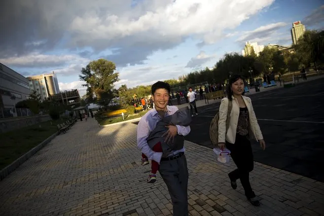 A man and woman smile as the man carries a baby through a park in central Pyongyang October 11, 2015. (Photo by Damir Sagolj/Reuters)