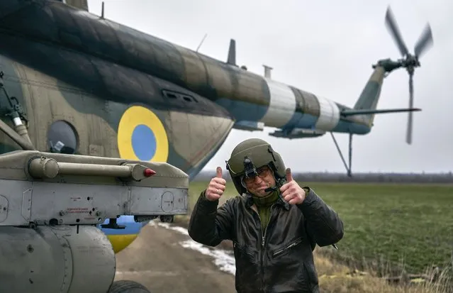 A pilot shows thumbs up before a combat flight standing near his helicopter at a Ukrainian military air base close to the frontline in the Kherson region, Ukraine, Sunday, January 8, 2023. (Photo by LIBKOS/AP Photo)