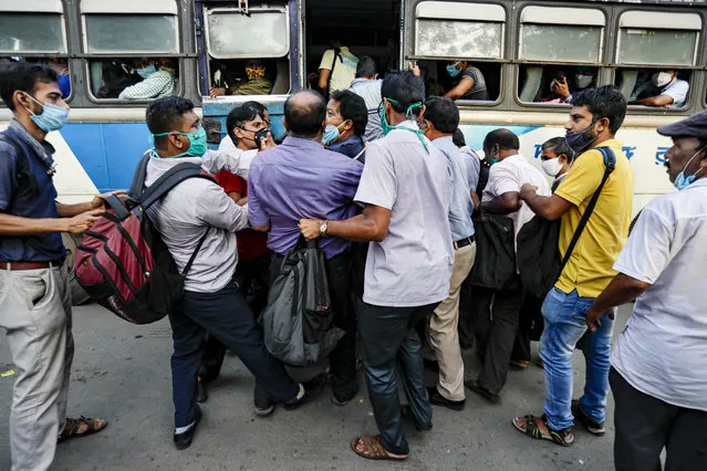 Commuters ignoring physical distancing norms push each other as they try to board on a long distance bus in Kolkata, India, Thursday, October 1, 2020. India is expected to become the coronavirus pandemic's worst-hit country within weeks, surpassing the United States. (Photo by Bikas Das/AP Photo)