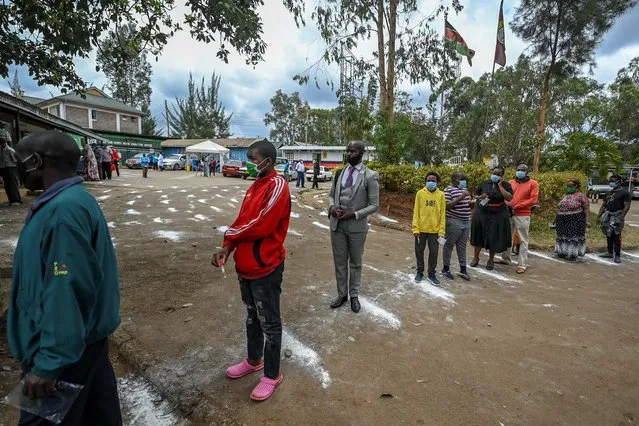 People stand on white-powder markers on the ground to adhere to social distance measures as they wait to be tested during a mass testing for COVID-19 coronavirus provided free of charge by the Kenyan government in the Kibera slum in Nairobi on October 18, 2020. The Nairobi Metropolitan Services (NMS) commenced a free COVID-19 coronavirus mass testing exercise across Nairobi for two days following a surge in numbers of cases testing positive for the COVID-19 coronavirus around the country, where an easing of restrictions including mask wearing, curfew hours, re-opening of schools and bars and social distancing in some public spaces is feared may trigger a resurgence. (Photo by Tony Karumba/AFP APhoto)