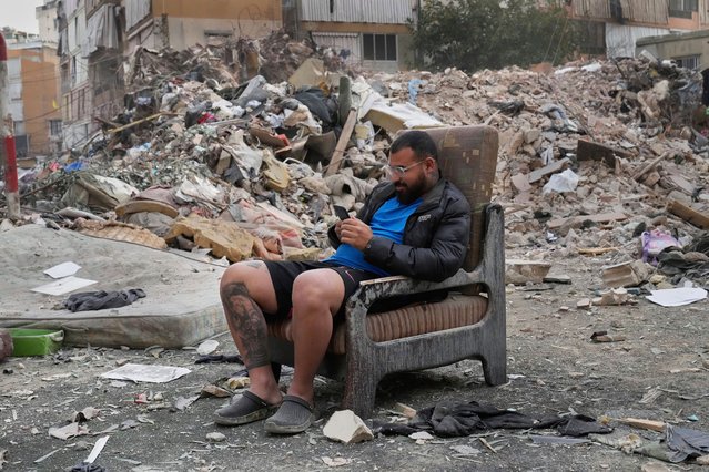 A man sits on a chair checks his mobile phone at the site where an Israeli airstrike hit a building in Dahiyeh, a southern suburb of Beirut, Lebanon, early Tuesday, April 1, 2025. (Photo by Hussein Malla/AP Photo)