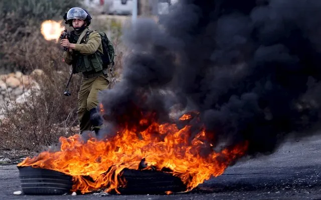 An Israeli soldier fires a weapon towards Palestinian protesters during clashes near the Jewish settlement of Bet El, near the West Bank city of Ramallah October 30, 2015. Knife-wielding Palestinians attacked Israelis in Jerusalem and the Israeli-occupied West Bank on Friday and one assailant was shot dead, police said, extending a wave of violence spurred in part by tensions over a Jerusalem holy site. (Photo by Mohamad Torokman/Reuters)