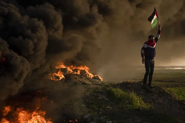 Palestinians burn tires and wave the national flag during a protest against Israeli military raid in the West Bank city of Jenin, along the border fence with Israel, in east of Gaza City, Thursday, January 26, 2023. During the raid in the West Bank town of Jenin, Israeli forces killed at least nine Palestinians, including a 60-year-old woman, and wounded several others, Palestinian health officials said, in one of the deadliest days of fighting in years. The Israeli military said it was conducting an operation to arrest militants when a gun battle erupted. (Photo by Fatima Shbair/AP Photo)