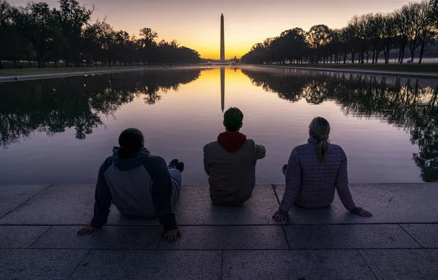 A trio of friends watch the sunrise at the Reflecting Pool near the Lincoln Memorial in Washington, Thursday, November 5, 2020, two days after Election Day. (Photo by J. Scott Applewhite/AP Photo)