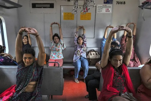 Commuters in a suburban train take part in a yoga session to mark the International Women's Day in Mumbai, India, Wednesday, March 8, 2023. (Photo by Rafiq Maqbool/AP Photo)