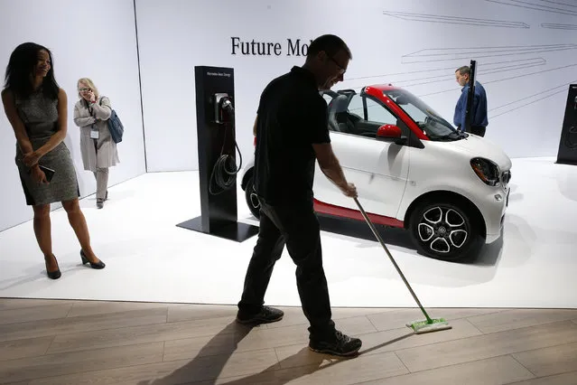 A worker sweeps the floor near a Smart car Fortwo Dlectric Drive at the New York Auto Show in the Manhattan borough of New York City, New York, U.S., March 28, 2018. (Photo by Brendan McDermid/Reuters)