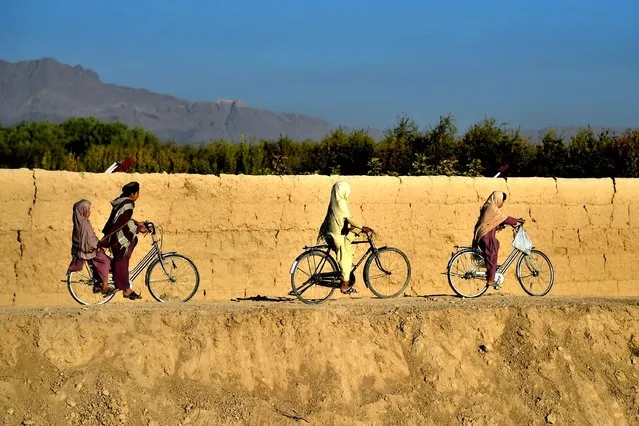 Youths ride their byciles along a road in Dand district of Kandahar province on October 1, 2020 (Photo by Wakil Kohsar/AFP Photo)