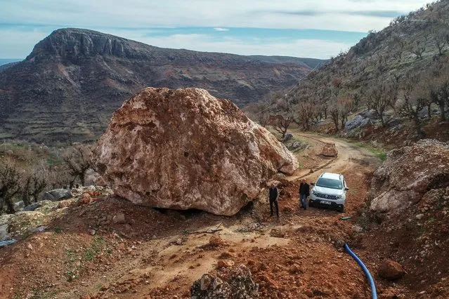 An aerial view shows people inspect the massive stone, being tangent to Alidam village, 45 km away from the Kahta district of Adiyaman, Turkiye after 7.7 and 7.6 magnitude earthquakes hit multiple provinces of Turkiye on March 07, 2023. Stones, rolling from the mountain, damaged trees, sewage system and water supply network. On Feb. 06, a strong 7.7 earthquake, centered in the Pazarcik district, jolted Kahramanmaras and strongly shook several provinces, including Gaziantep, Sanliurfa, Diyarbakir, Adana, Adiyaman, Malatya, Osmaniye, Hatay, Kilis, and Elazig. Later, at 1.24 p.m. (1024GMT), a 7.6 magnitude quake centered in Kahramanmaras' Elbistan district struck the region. (Photo by Ozkan Bilgin/Anadolu Agency via Getty Images)