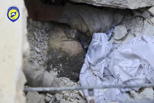In this picture taken, Tuesday, October 11, 2016, provided by the Syrian Civil Defense group known as the White Helmets, the body of a child is seen under the rubble in rebel-held eastern Aleppo, Syria. (Photo by Syrian Civil Defense- White Helmets via AP Photo)