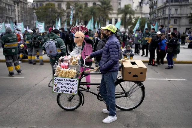 A street vender offers candy on the sidelines of a protest demanding more money for social programs that support the unemployed in Buenos Aires, Argentina, Wednesday, August 17, 2022. (Photo by Natacha Pisarenko/AP Photo)