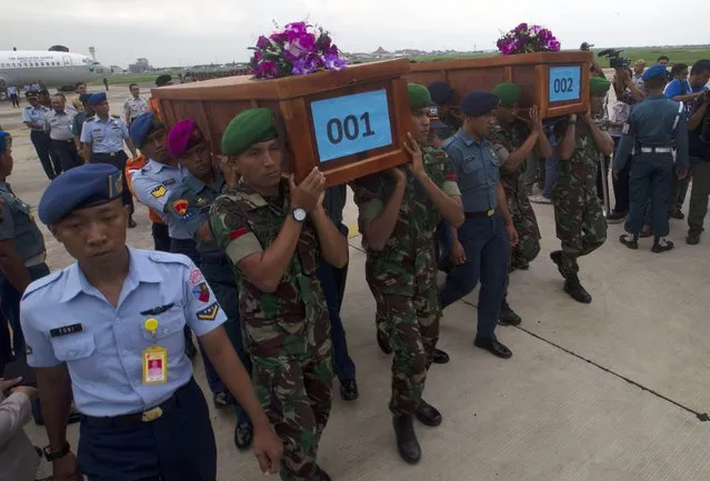 Indonesian military carry the caskets containing the bodies of two AirAsia flight QZ8501 passengers recovered off the coast of Borneo at a military base in Surabaya December 31, 2014. (Photo by Sigit Pamungkas/Reuters)