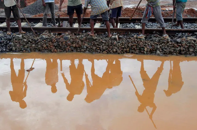 Labourers are reflected in a puddle as they work at the installation site of a new railway track on the outskirts of Agartala, India, October 13, 2016. (Photo by Jayanta Dey/Reuters)