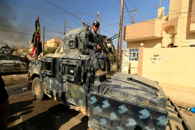 A member of Iraqi security forces sits on a military vehicle as displaced people who fled Hammam al-Alil, south of Mosul, head to safer territory, Iraq November 6, 2016. (Photo by Thaier Al-Sudaini/Reuters)