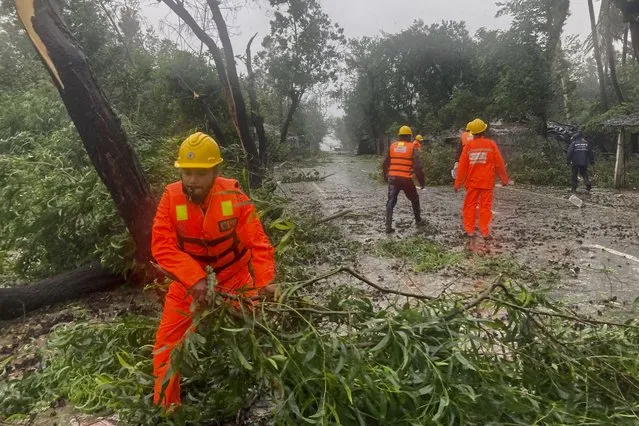 Rescue workers remove the fallen tress after a storm in Teknaf, near Cox's Bazar, Bangladesh, Sunday, May 14, 2023. Bangladesh and Myanmar braced Sunday as a severe cyclone started to hit coastal areas and authorities urged thousands of people in both countries to seek shelter. (Photo by Al-emrun Garjon/AP Photo)