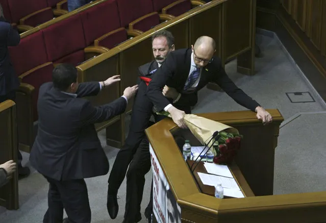 Oleh Barna, a Ukrainian lawmaker from the Block of Petro Poroshenko, second left, tries pull Ukrainian Prime Minister Arseniy Yatsenuk out from the podium during his speech at a parliamentary session in the Parliament in Kiev, Ukraine, Friday December 11, 2015. (Photo by Volodymyr Tarasov/AP Photo)