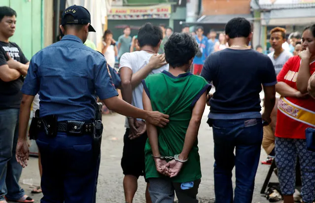 Policemen escort two men who were detained because of pending criminal court cases, during an anti-drugs operation in Mandaluyong, Metro Manila in the Philippines, November 10, 2016. (Photo by Erik De Castro/Reuters)