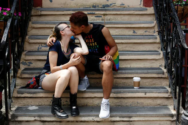 Davy Ran kisses their partner James Brice on a stoop before the 2018 New York City Pride Parade in Manhattan, New York, June 24, 2018. (Photo by Andrew Kelly/Reuters)