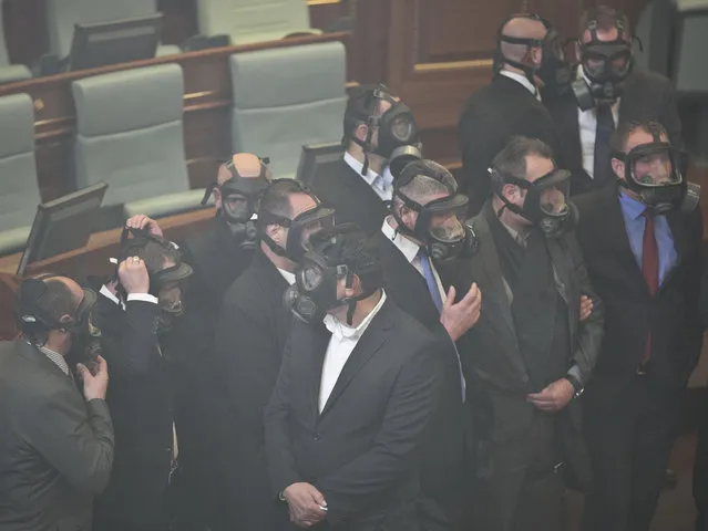Kosovo parliament security wear gas masks after opposition lawmakers released a tear gas canister disrupting a parliamentary session in Kosovo capital Pristina on Monday December 14, 2015. Opposition lawmakers have released tear gas in Kosovo's parliament in their latest attempt to pressure the government into renouncing deals with Serbia and Montenegro. (Photo by Visar Kryeziu/AP Photo)
