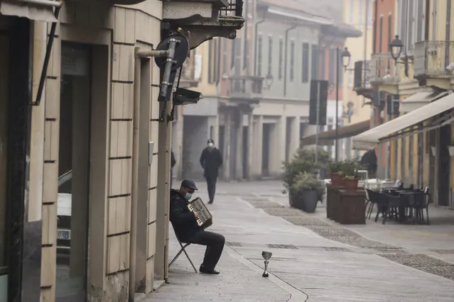 A man plays an accordion in Codogno, northern Italy, Sunday, February 21, 2021. The first case of locally spread COVID-19 in Europe was found in the small town of Codogno, Italy one year ago on February 21st, 2020. The next day the area became a red zone, locked down and cutoff from the rest of Italy with soldiers standing at roadblocks keeping anyone from entering of leaving. (Photo by Luca Bruno/AP Photo)