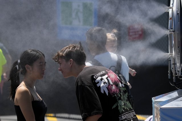 Fans cool down at a water mister machine at Melbourne Park venue for the Australian Open tennis championships in Melbourne, Australia, Tuesday, January 14, 2025. (Photo by Manish Swarup/AP Photo)