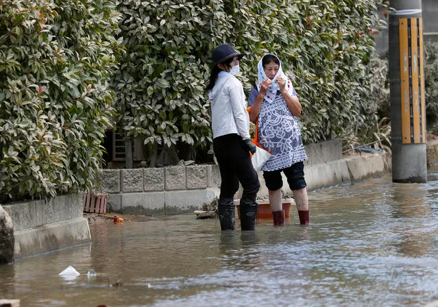 Local residents stand in a flooded area in Mabi town in Kurashiki, Okayama Prefecture, Japan, July 10, 2018. (Photo by Issei Kato/Reuters)