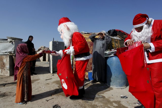 Volunteers wearing Santa Claus costumes distribute presents to children at a poor community in Najaf, south of Baghdad, December 19, 2015. (Photo by Alaa Al-Marjani/Reuters)