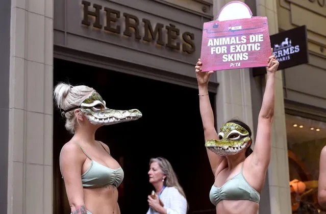 Activists from the animal rights group PETA, wearing bikinis and crocodile masks, stand outside a store of the French fashion label Hermes in Melbourne on March 16, 2021, to protest against their use of crocodile skins and the recent purchases by Hermes and LVMH of crocodile farms in Australia's Northern Territory. (Photo by William West/AFP Photo)