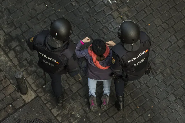 Riot police drag an activist from blocking the door to stop Jessica Bernice Michelena and her family's eviction together in Madrid, Spain, Tuesday, February 3, 2015. Jessica, 40 years old, and her partner, Eduardo Lucas Zambrano, 37 years old, unemployed and their children: Miguel Angel, 7, Ana Mile Lucas, 5, occupied an apartment 5 months ago after she lost her job, was evicted from a previous place and lived in the street with her children for 15 days. (Photo by Andres Kudacki/AP Photo)