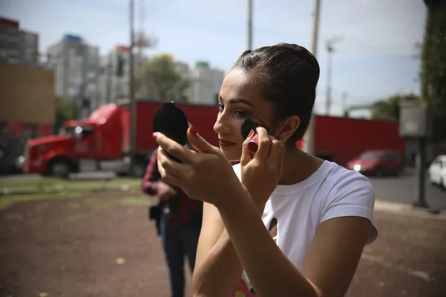 A ballet dancer brushes on blush as she prepares for a street ballet performance in Mexico City, Saturday, July 28, 2018. (Photo by Emilio Espejel/AP Photo)