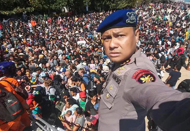 A handout photo made available by the Indonesian West Nusa Tenggara Marine Police shows Chief of the Marine Police of Lombok, Dewa Wijaya (front) taking a picture in front of hundreds of local and foreign tourists gathering on the beach after an earthquake, in an attempt to leave Gili Trawangan Island, a neighboring island of Lombok, West Nusa Tenggara, Indonesia, 06 August 2018. According to media reports, a 7.0 magnitude quake hit Indonesia's island of Lombok on 05 August killing at least 91 people. (Photo by Polairud Polda Ntb/EPA/EFE)
