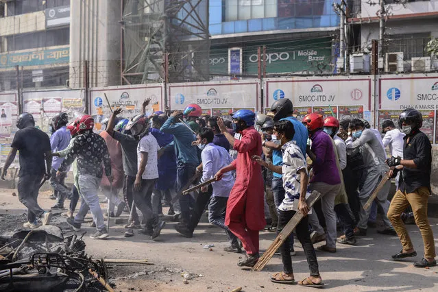 A group of protestors walk with wooden sticks  during a clash with another group  after Friday prayers at Baitul Mokarram mosque in Dhaka, Bangladesh, Friday, March 26, 2021. (Photo by Mahmud Hossain Opu/AP Photo)