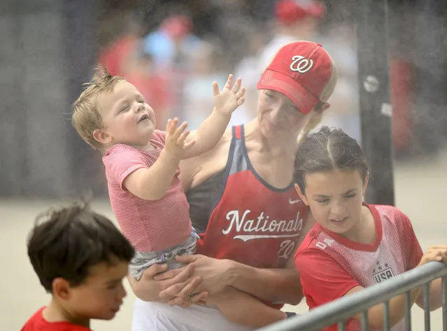 Christine Barrett of Reston cools down with her one year old son Grant as the Cincinnati Reds and Washington Nationals play at Nationals Park on July 4, 2023.  (Photo by Jonathan Newton/The Washington Post)