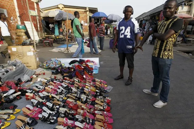 Men stand next to shoes on display on the eve of Christmas at Wuse market in Abuja, Nigeria December 24, 2015. (Photo by Afolabi Sotunde/Reuters)