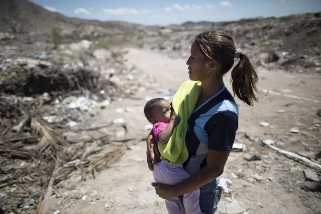 Marbelis Brito holds her 7-month daughter Antonela at the Pavia garbage dump where her family searches for valuable items to sell on the outskirts of Barquisimeto, Venezuela, Wednesday, March 3, 2021. The 35-year-old mother of eight grew up here with her mother, who also survived by reselling items found in the dump. (Photo by Ariana Cubillos/AP Photo)