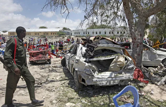 A Somali soldier walks near the wreckage of vehicles at the scene of a blast outside the compound of a district headquarters in the capital Mogadishu, Somalia Sunday, September 2, 2018. A Somali police officer says a number of people are wounded after a suicide bomber detonated an explosives-laden vehicle at a checkpoint outside the headquarters after being stopped by security forces. (Photo by Farah Abdi Warsameh/AP Photo)