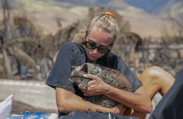A woman cradles her cat after finding him in the aftermath of a wildfire in Lahaina, western Maui, Hawaii on August 11, 2023. A wildfire that left Lahaina in charred ruins has killed at least 67 people, authorities said on August 11, making it one of the deadliest disasters in the US state's history. Brushfires on Maui, fueled by high winds from Hurricane Dora passing to the south of Hawaii, broke out August 8 and rapidly engulfed Lahaina. (Photo by Moses Slovatizki/AFP Photo)