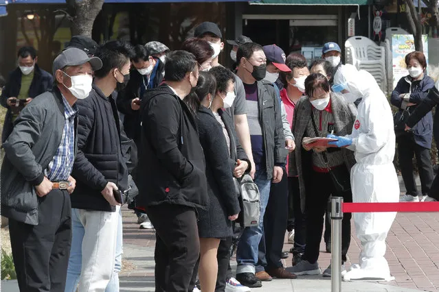 A health official checks names of migrant workers as they wait for coronavirus testing at a makeshift clinic in Seoul, South Korea, Friday, March 19, 2021. Britain's ambassador to South Korea on Thursday criticized South Korean health authorities for mandating coronavirus tests on all foreign workers in capital Seoul and nearby Gyeonggi Province in a mass testing campaign that has triggered complaints about racial discrimination. (Photo by Ahn Young-joon/AP Photo)