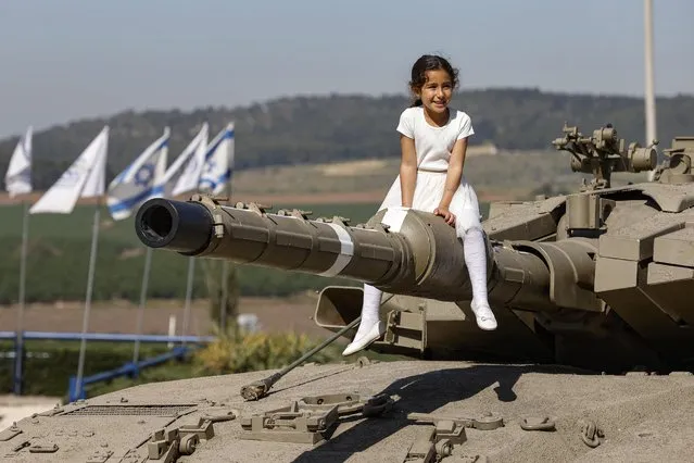 A girl sits on the barrel of a tank turret at the Israeli Armoured Corps memorial in Latrun, between Jerusalem and Tel Aviv, on April 14, 2021, following a ceremony commemorating Yom HaZikaron (Israel's Remembrance Day for fallen soldiers). Israel annually marks Yom HaZikaron to commemorate 23,928 fallen soldiers and fighters since 1860, just before the celebrations marking the Jewish State's 73rd anniversary, according to the Jewish calendar. (Photo by Jack Guez/AFP Photo)