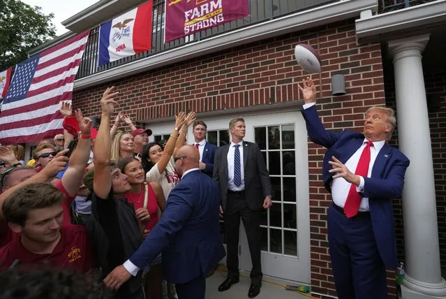Former President Donald Trump throws a football to the crowd during a visit to the Alpha Gamma Rho, agricultural fraternity, at Iowa State University before an NCAA college football game between Iowa State and Iowa, Saturday, September 9, 2023, in Ames, Iowa. (Photo by Charlie Neibergall/AP Photo)