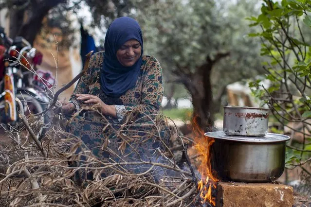 A Syrian refugee cooks food on a fire, at an informal refugee camp, in the town of Rihaniyye in the northern city of Tripoli, Lebanon, Thursday, April 8, 2021. (Photo by Hassan Ammar/AP Photo)