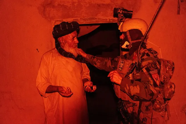 A member of the Afghan Special Forces speaks to a resident as others search his house during a mission against Taliban, in Kandahar province, Afghanistan, July 12, 2021. (Photo by Danish Siddiqui/Reuters)