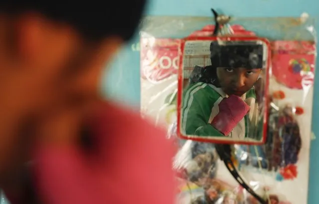 Gracce Kelly Flores, a 12-year-old boxer who goes by the nickname Hands of Stone, strikes a pose in the mirror hanging in her kitchen after her morning workout in Palca, Bolivia, early Thursday, June 10, 2021. At age 8, Flores defeated a 10-year-old boy, and with three national boxing medals under her belt, she dreams of reaching the women's boxing world championship. (Photo by Juan Karita/AP Photo)