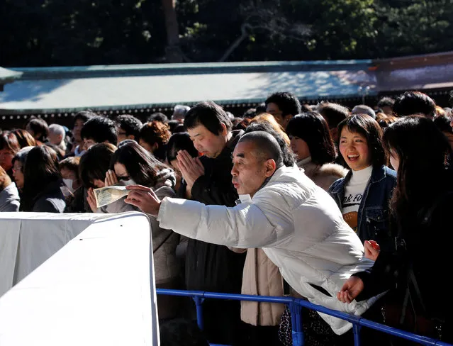 A man throws money into a giant offering box on the first day of the new year at Meiji Shrine in Tokyo, Japan, January 1, 2017. (Photo by Kim Kyung-Hoon/Reuters)